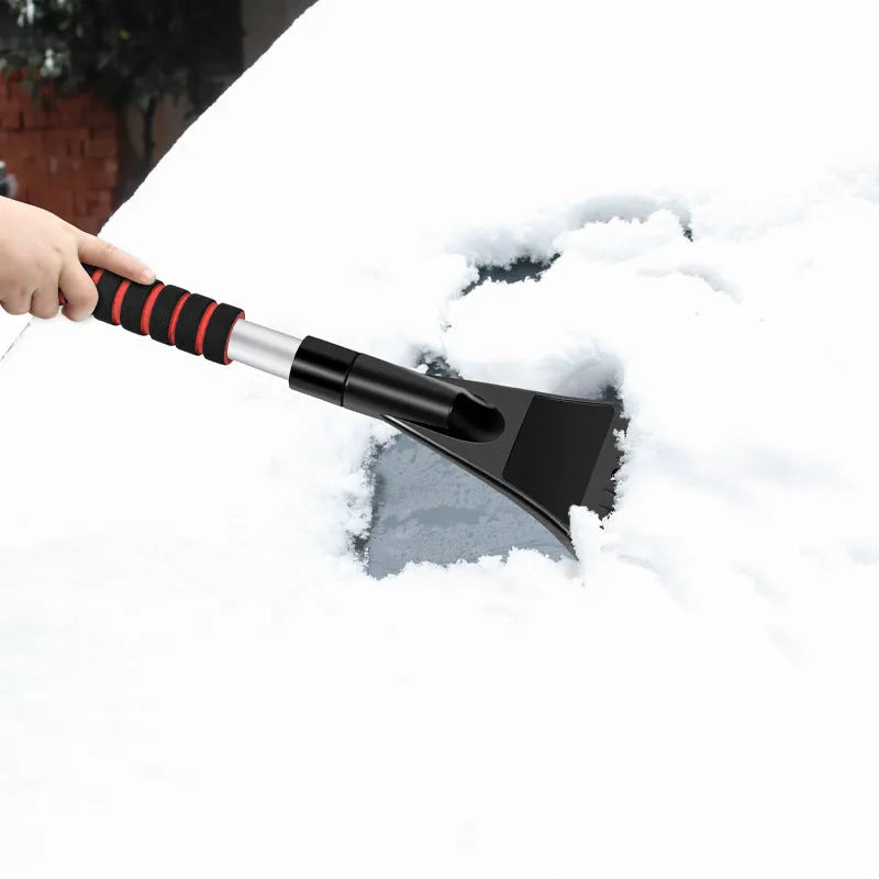 Car deicing shovel with black ABS plastic shovel head and brush, telescopic handle extended, on a windscreen with frost