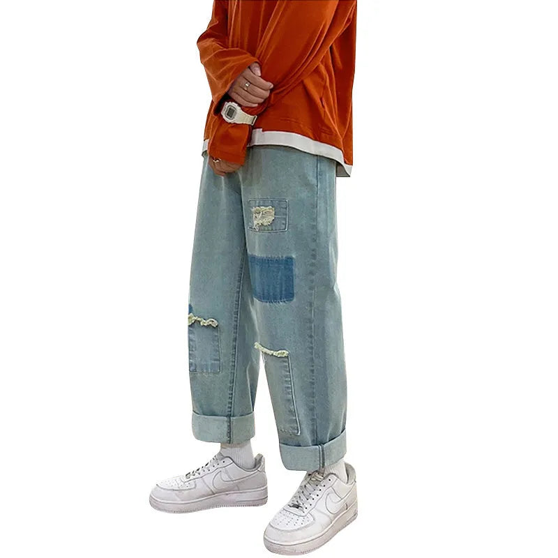 Men's high street ripped jeans with loose straight leg fit in black, showing rips on front thigh area
