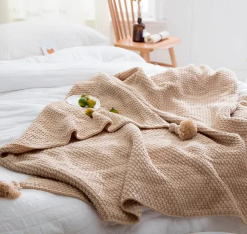 Nordic-style fringed knit ball acrylic blanket in beige colour, laid flat showing its 130x170cm size.