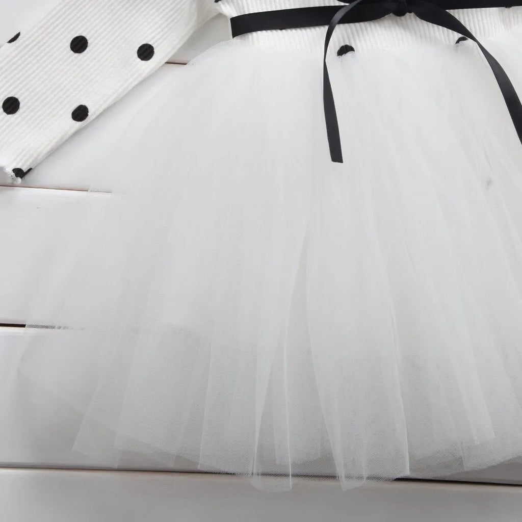 Baby girl wearing a long sleeve white lace tutu dress for a christening or birthday party.