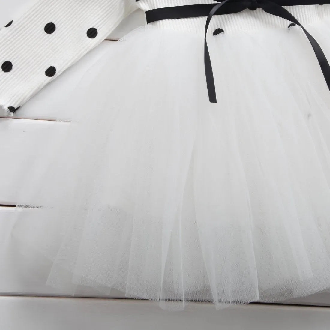 Baby girl wearing a long sleeve white lace tutu dress for a christening or birthday party.
