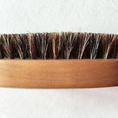 Natural boar beard brush for men in black finish with dense bristles on a table