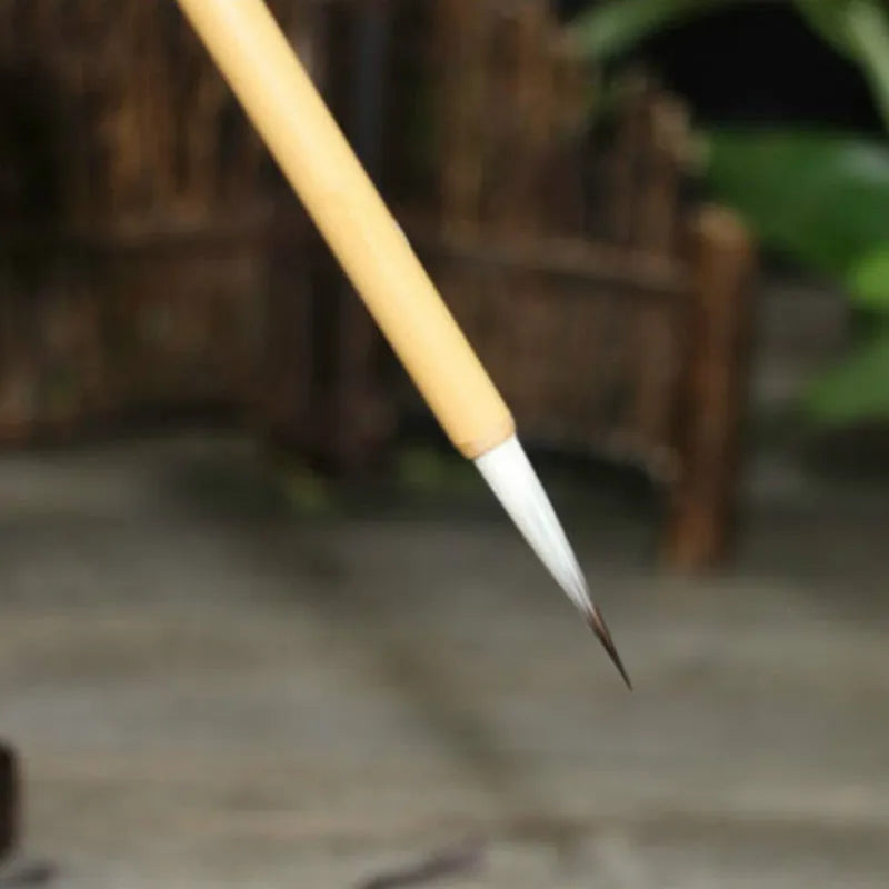 Set of four gold-handled writing brushes with mixed hair bristles for calligraphy.