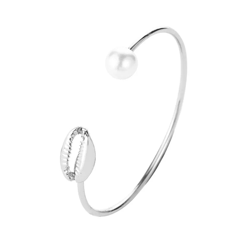 Alloy opening bracelet with pearl and shell decoration in gold finish on white background