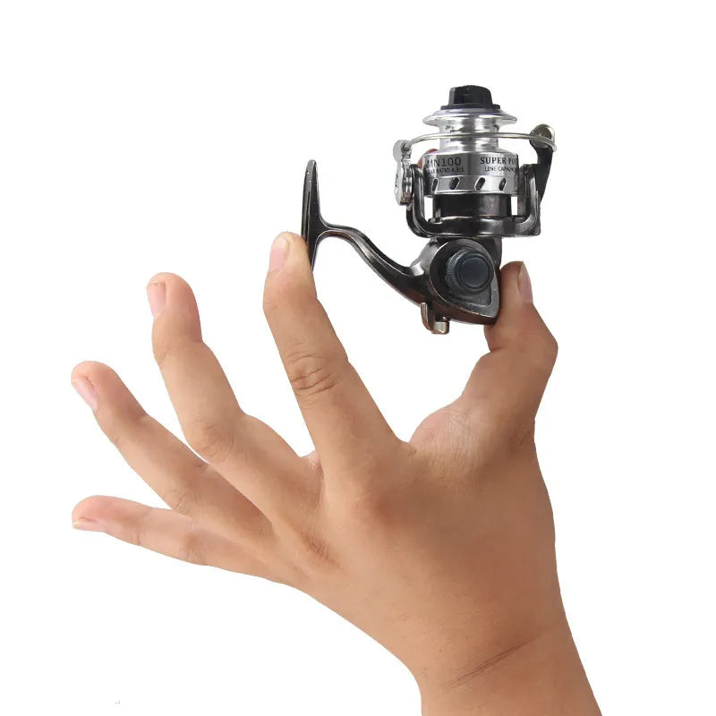 Mini 100 all metal fishing reel in black, 8cm high, with wooden handle rocker arm folded