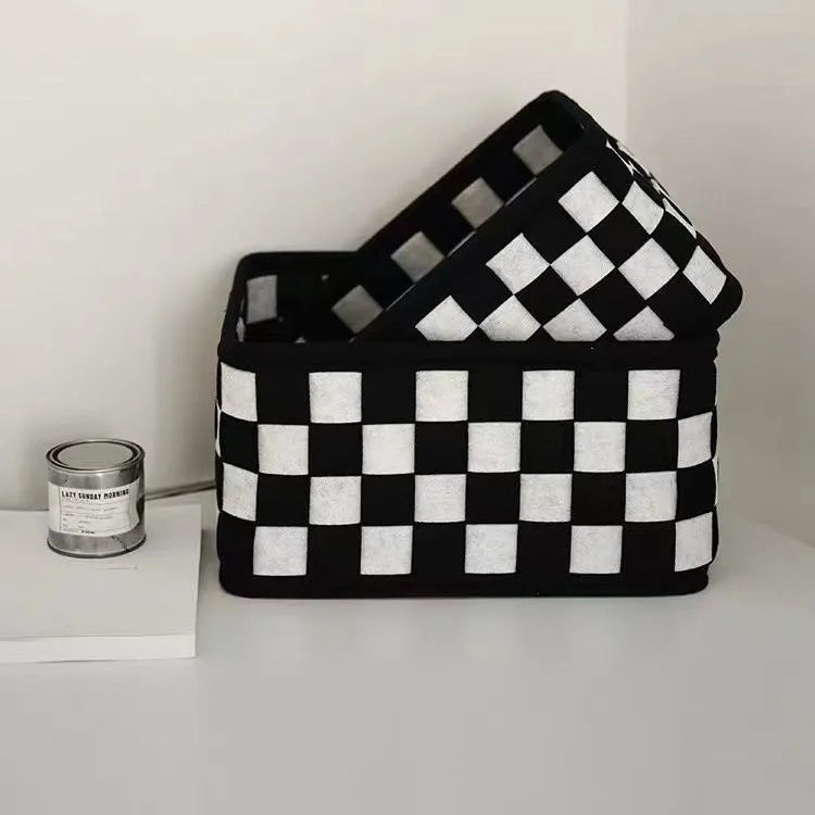 Checkerboard patterned grey felt storage basket with folded sides, shown empty.