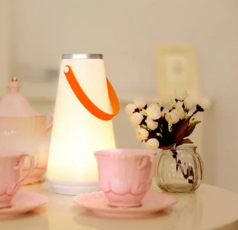 White rechargeable LED table lamp with USB cable on a wooden surface.