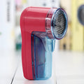White portable electric lint remover for clothing on a table.