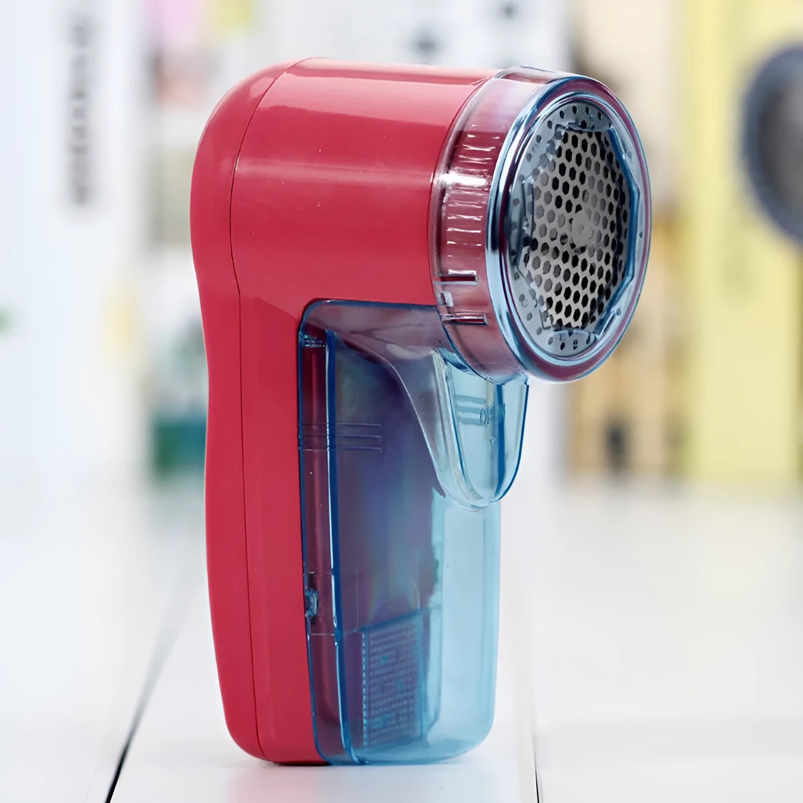 White portable electric lint remover for clothing on a table.