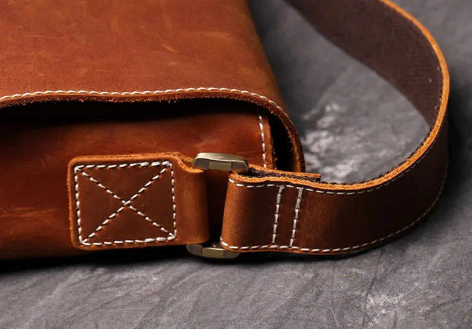 Brown vintage leather men's messenger bag with a shoulder strap showing internal organiser pockets.