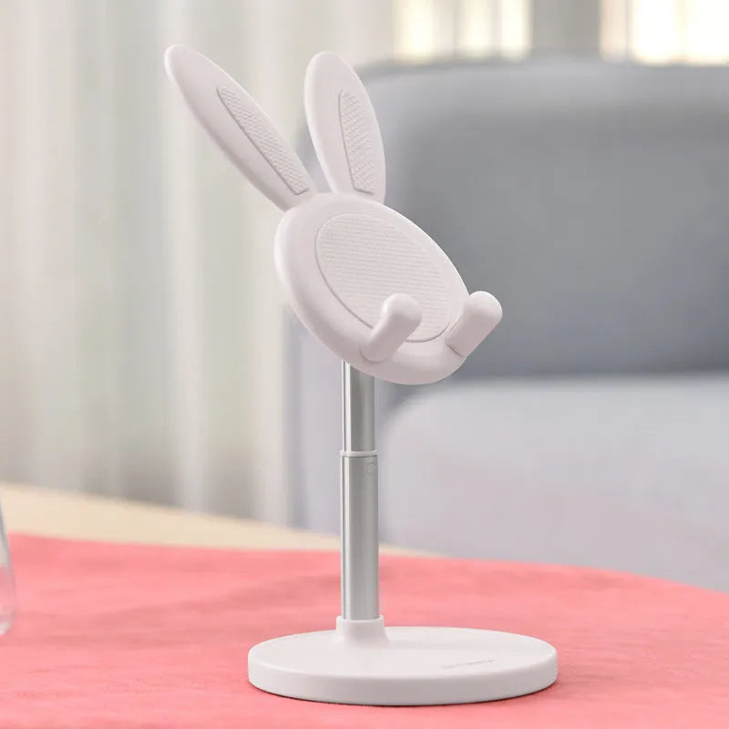 Silicone rabbit phone stand in pink on a desk holding a smartphone at an adjustable angle