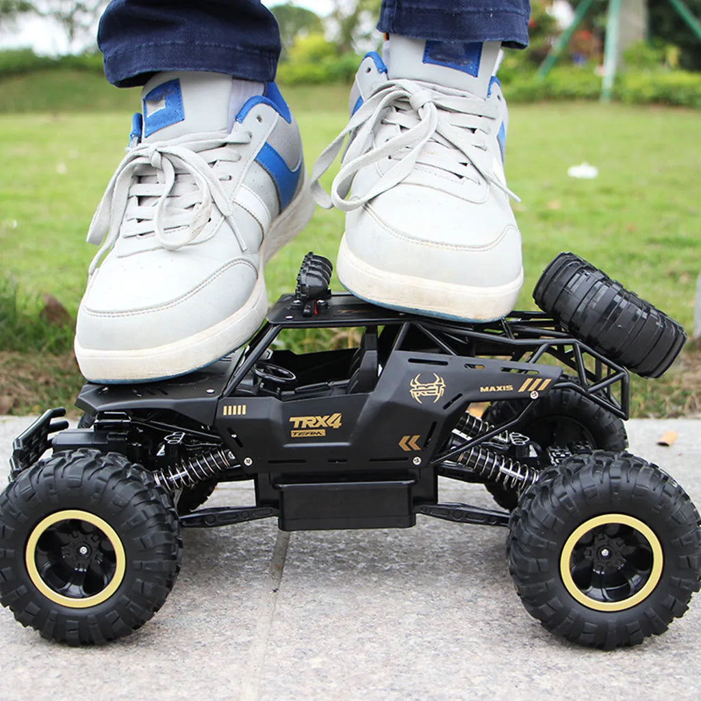 Large black 4WD remote control off-road climbing car on a rocky surface.