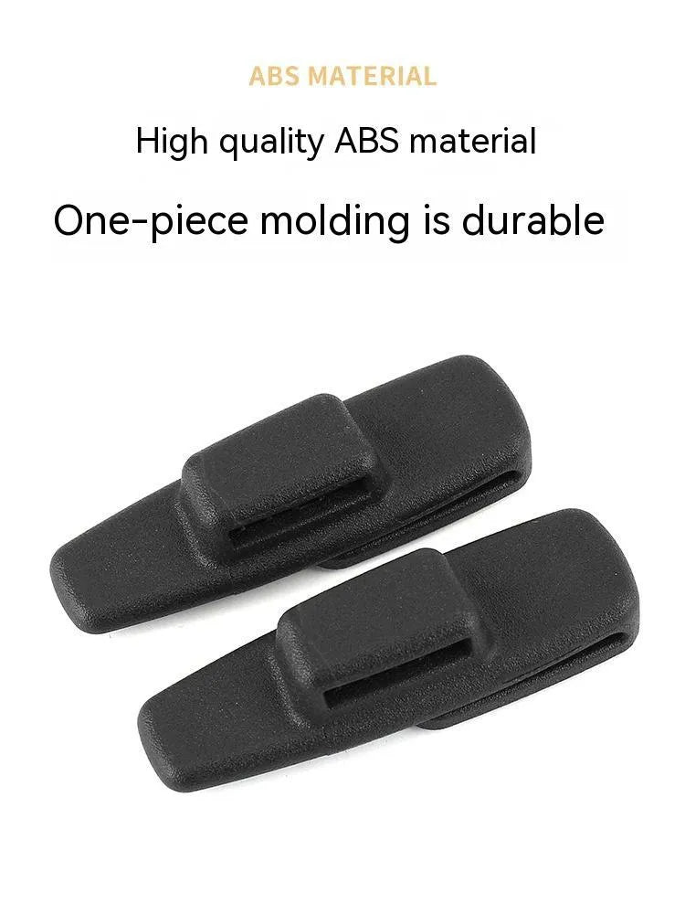 Two black ABS plastic universal seatbelt stopper clips shown next to a car seatbelt.