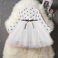 Baby girl wearing a long sleeve white lace tutu dress for a christening or birthday party.