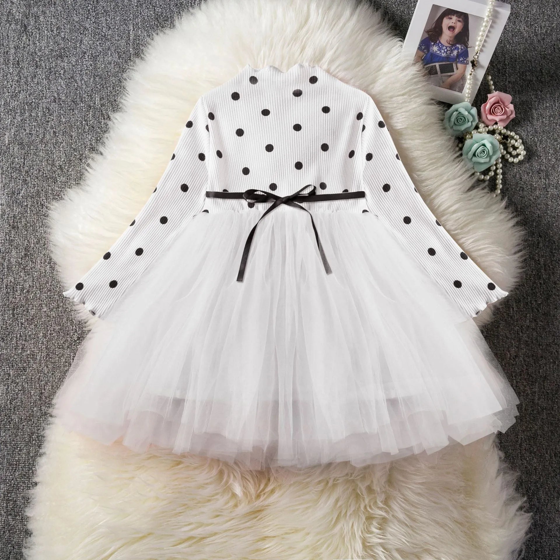 Baby girl wearing a long sleeve white lace tutu dress for a christening or birthday party.