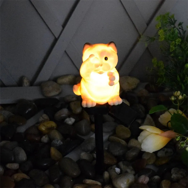 Brown cat-shaped solar lawn light in garden setting with LED illumination at dusk