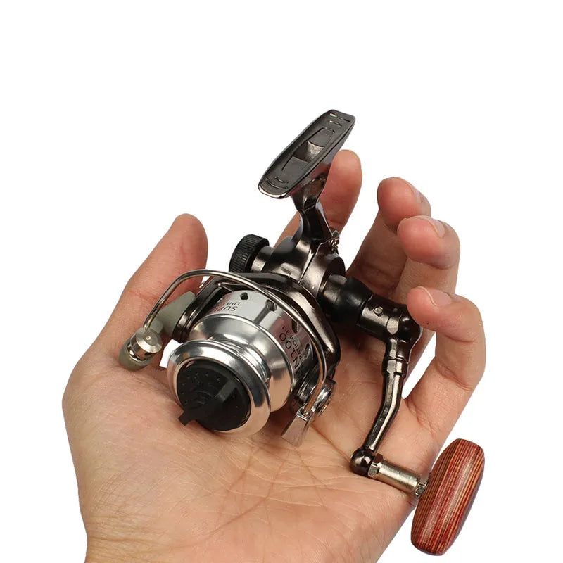 Mini 100 all metal fishing reel in black, 8cm high, with wooden handle rocker arm folded