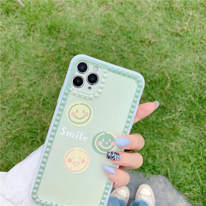 Green TPU iPhone case with geometric shapes and smiley faces inside a polka dot frame.