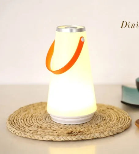 White rechargeable LED table lamp with USB cable on a wooden surface.