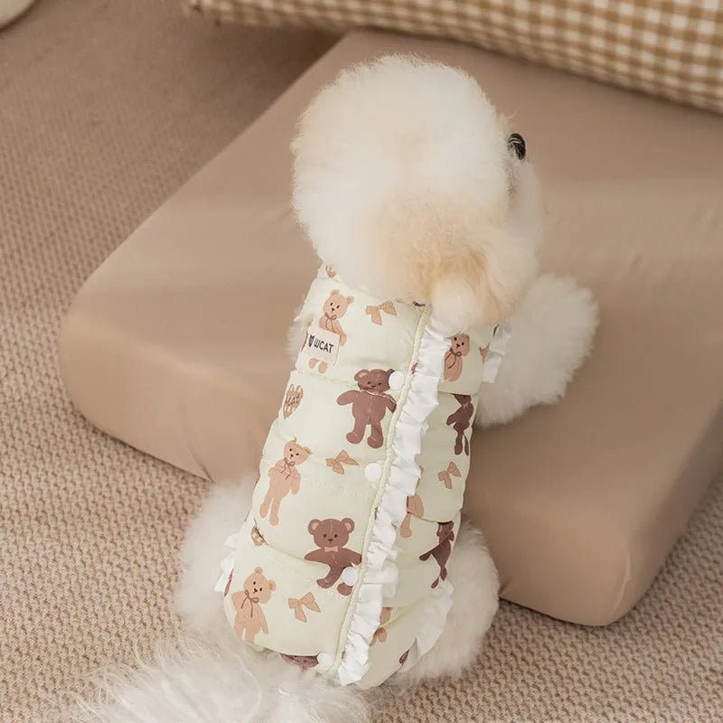Small dog wearing cream fleece jumpsuit with bear pattern and white ruffles