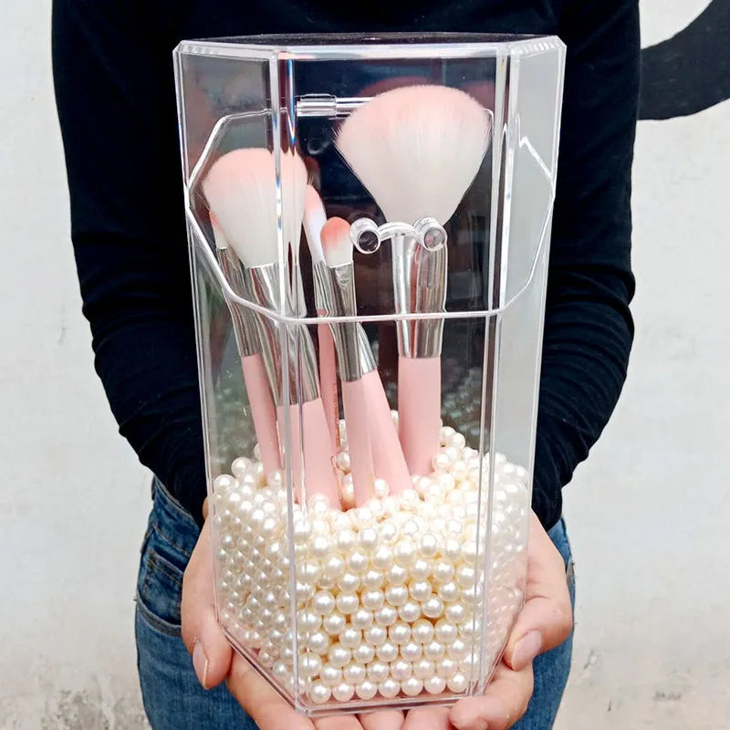 Clear acrylic makeup brush holder on a countertop with pearl coloured beads inside, measuring 12.3x10.6x21.5cm
