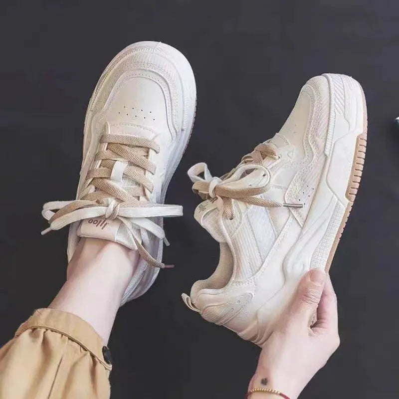 Women's beige and pink low-top lace-up sneakers with a rubber sole on a white background.