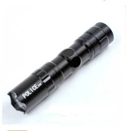 Black aluminium mini LED flashlight on a dark background, shown next to a AA battery for scale.