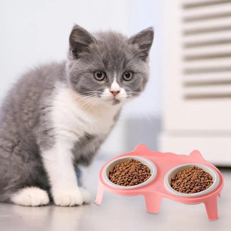 Blue ceramic cat food and water bowls on a white elevated plastic stand with a hook