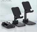 Black adjustable desk mobile phone holder with silicone grip on a wooden desk