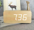 Rectangular wooden LED alarm clock with digital display showing time, temperature, and date, on a desk