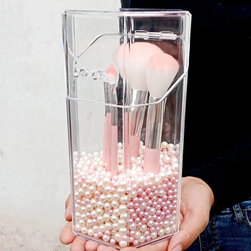 Clear acrylic makeup brush holder on a countertop with pearl coloured beads inside, measuring 12.3x10.6x21.5cm