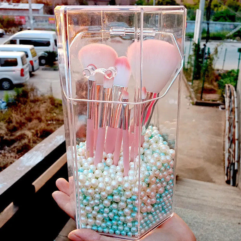 Clear acrylic makeup brush holder on a countertop with pearl coloured beads inside, measuring 12.3x10.6x21.5cm
