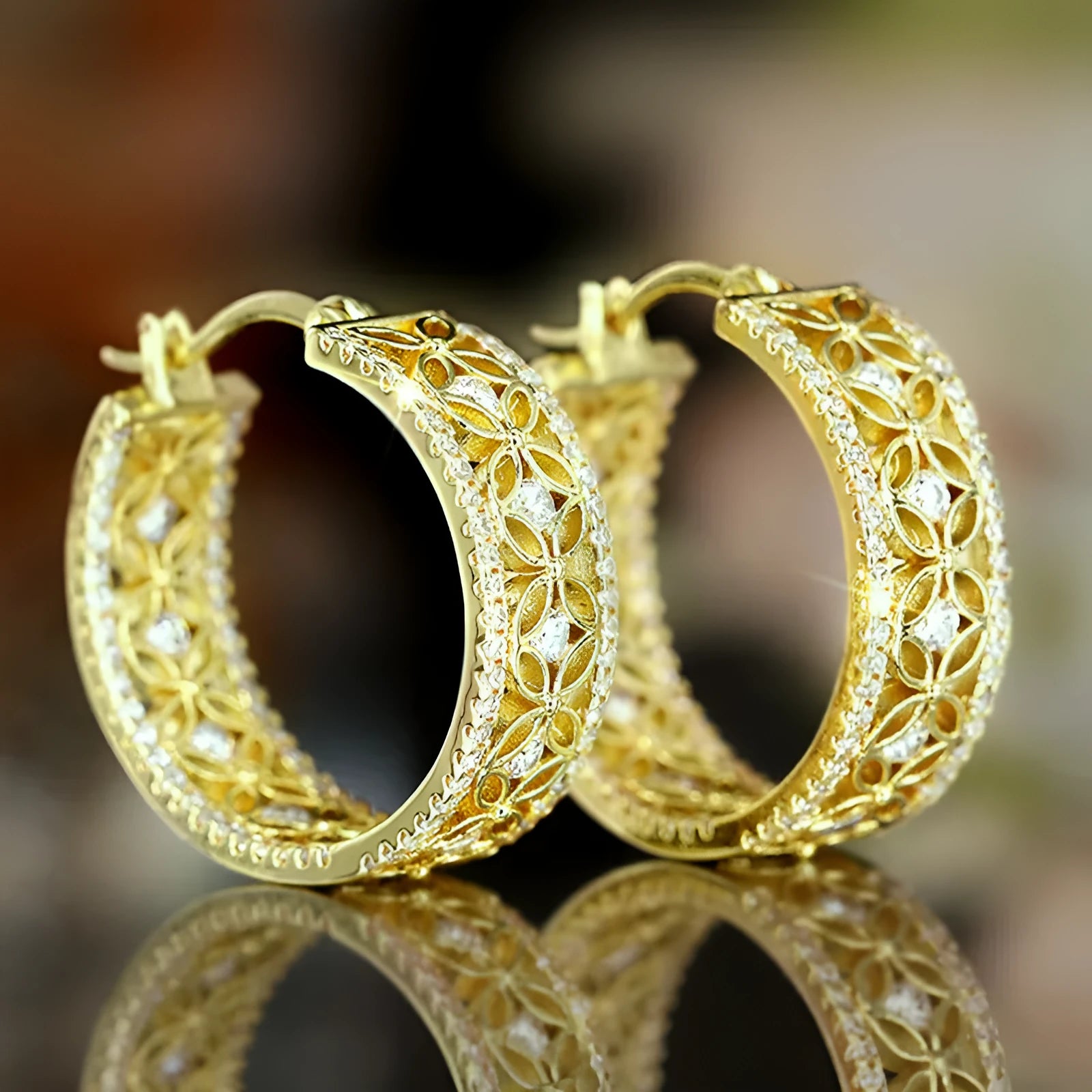 A pair of gold-coloured geometric butterfly earrings with floral details and horse eye styling on a white background.