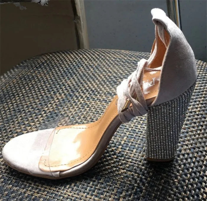 Black and gold pointed toe plastic high heel shoes on a white background.