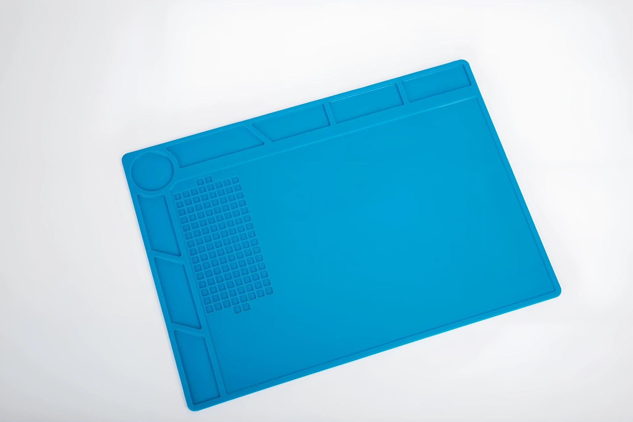 Blue silicone watch repair desk mat lying flat on a workbench.