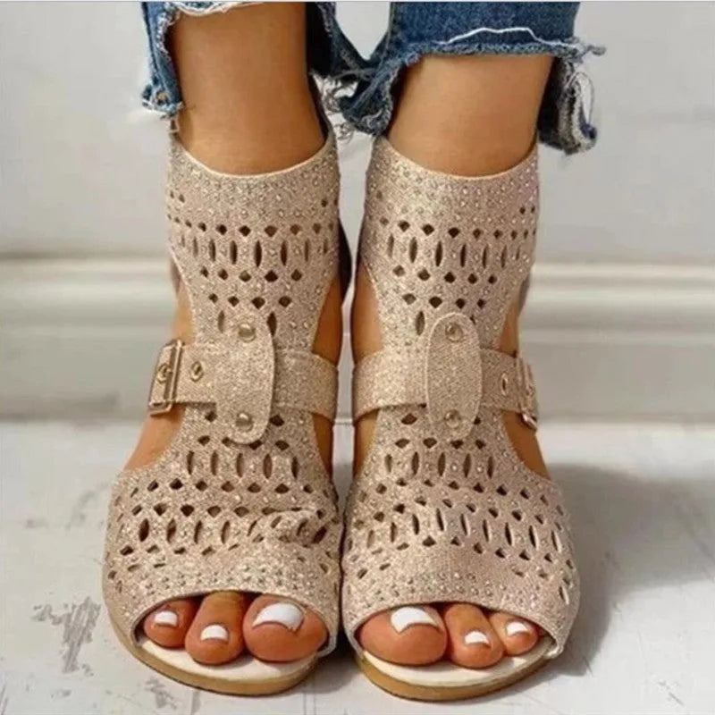 Women's beige rivet flat sandals showing fish mouth toe and back zipper closure on a wedge heel.
