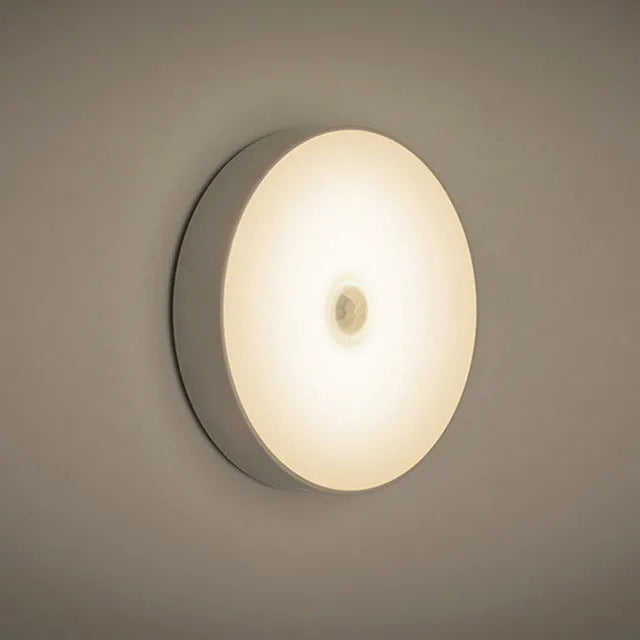 Small circular beige or white USB rechargeable body sensing LED night light with adhesive tape