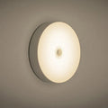 Small circular beige or white USB rechargeable body sensing LED night light with adhesive tape