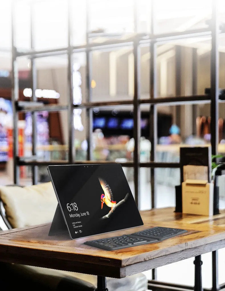 Folding Bluetooth keyboard in ABS with 64 keys, open on desk with iPad