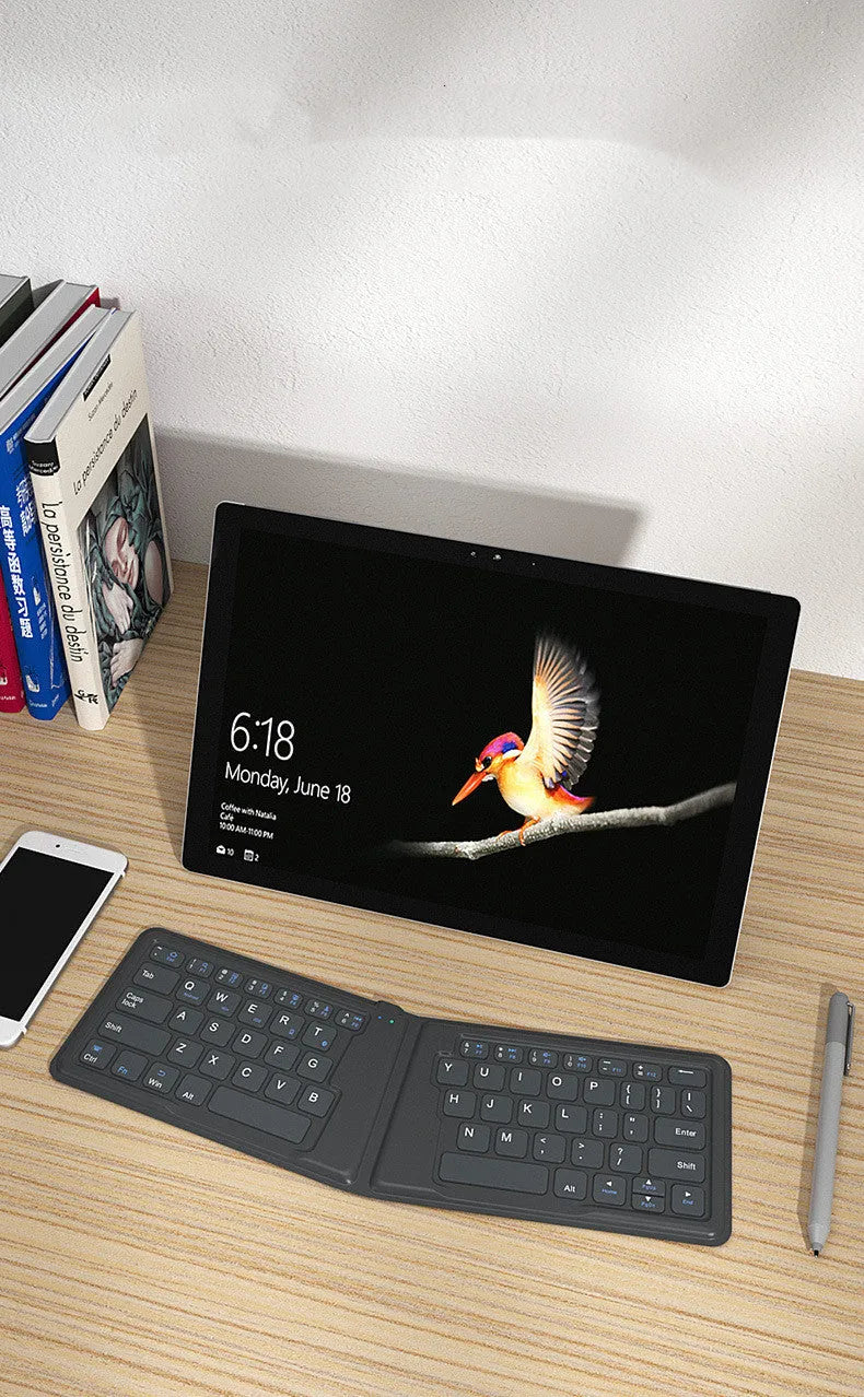 Folding Bluetooth keyboard in ABS with 64 keys, open on desk with iPad