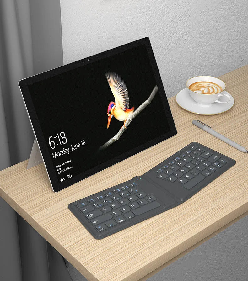 Folding Bluetooth keyboard in ABS with 64 keys, open on desk with iPad