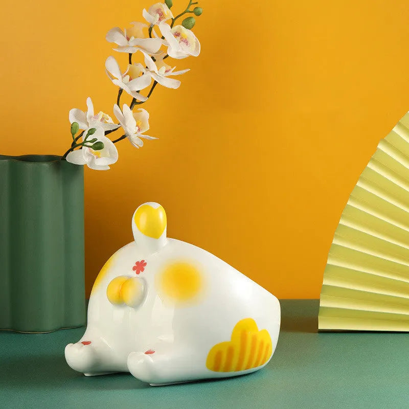 Ceramic pet bowl with inclined mouth and cartoon cat butt design, in white, on a wooden floor.