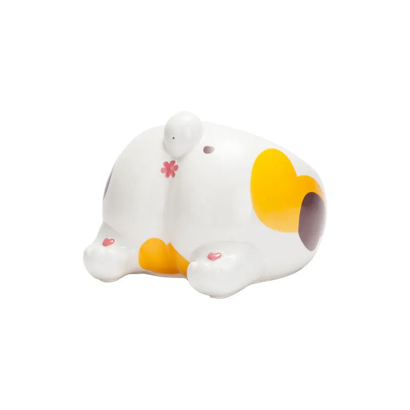 Ceramic pet bowl with inclined mouth and cartoon cat butt design, in white, on a wooden floor.