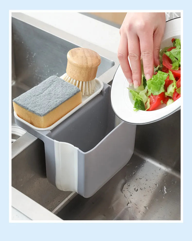 Foldable grey kitchen sink drain basket with suction cup hanging on sink edge