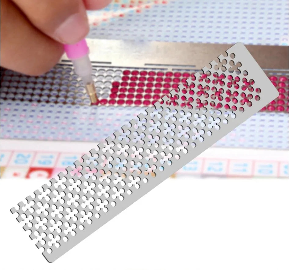 Stainless steel diamond painting grid ruler measuring 15cm by 3cm on a crafting table.