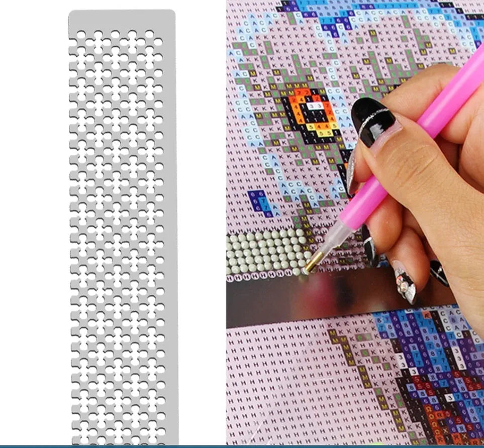 Stainless steel diamond painting grid ruler measuring 15cm by 3cm on a crafting table.