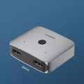 Grey Haibeisi HDMI switcher box with two input ports and one output port for 4K video sharing.