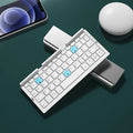 Silver white folding Bluetooth keyboard with integrated phone stand, shown open for typing and folded for storage