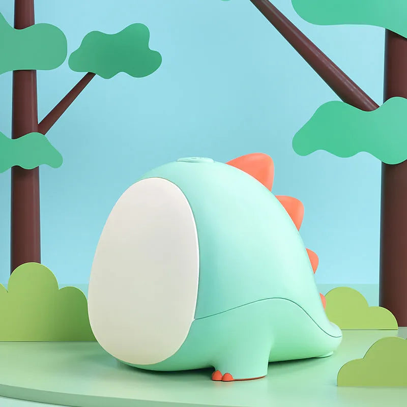 Green dinosaur silicone night light with USB charging cable on a bedside table