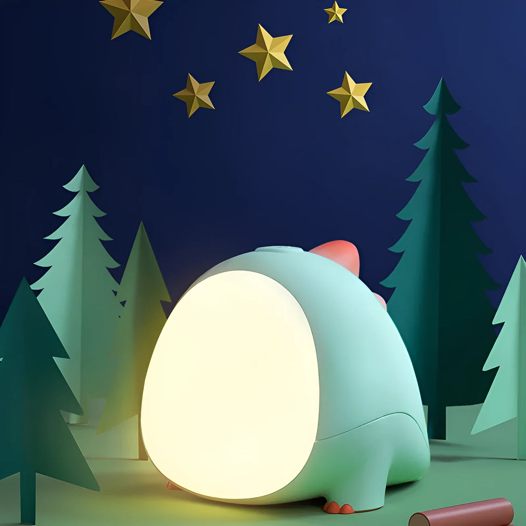 Green dinosaur silicone night light with USB charging cable on a bedside table
